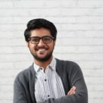 Portrait of confident handsome Indian man smiling and looking at camera